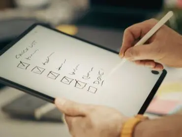 Les clés pour commencer désencombrer sa maison La photo d’une tablette numérique montrant une to do list tenue par deux mains