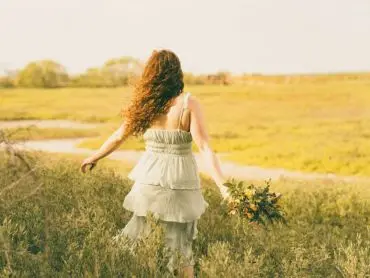 La photo d’une femme en robe d’été se promenant dans un champ illustrant le parcours de développement personnel du désencombrement de sa maison